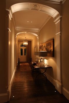 an archway leading to a hallway with wood floors and lighting on either side of it