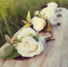 some white flowers are laying on a piece of wood in the grass and one flower is still attached to it