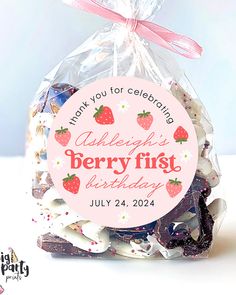 a bag filled with lots of cookies next to a pink tag that says happy berry first birthday