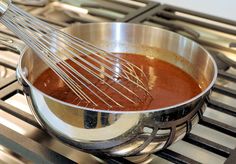 a pan filled with sauce and whisk on top of an oven