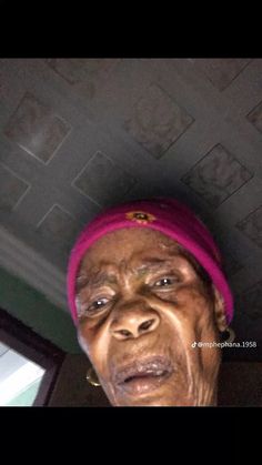 an old woman wearing a pink headband and looking up at the camera with her eyes wide open