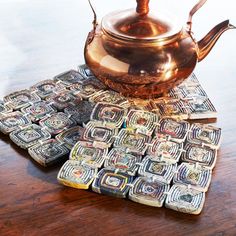 a tea pot sitting on top of a wooden table next to stacks of dollar bills