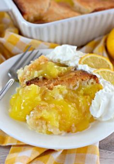 a slice of lemon cobbler on a plate with whipped cream and lemon wedges