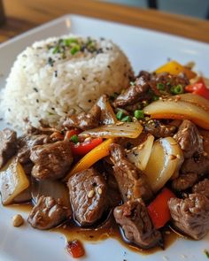 a white plate topped with meat and vegetables next to rice on top of a wooden table