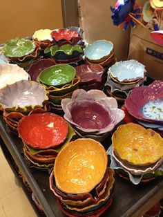 a table topped with lots of different colored bowls and plates on top of it's sides