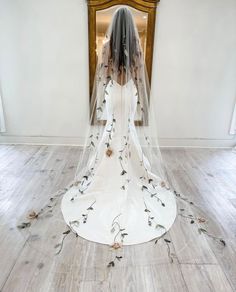 a woman in a white wedding dress with flowers on the floor and veil over her head