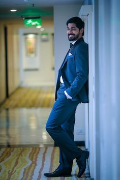 a man in a suit leaning against a wall