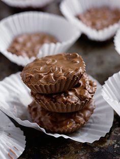 three chocolate cups stacked on top of each other in white paper wrappers, with one filled with chocolate