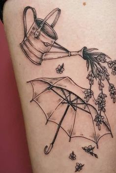 a woman's thigh with flowers and an umbrella tattoo on her leg that is pouring water from a watering can