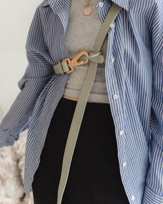 a woman wearing a blue and white striped shirt with a brown leather belt around her waist