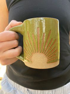 a person holding a green coffee mug in their hands