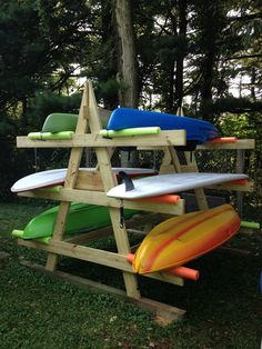 several surfboards are stacked on top of each other in the grass near some trees