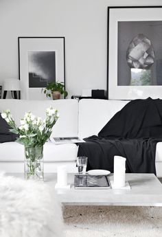 a living room filled with white furniture and pictures on the wall above it's coffee table