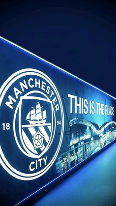 the manchester city sign is lit up in blue and has an image of a ship on it