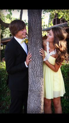 a man and woman standing next to each other near a tree