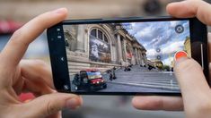 someone taking a photo with their cell phone in front of an old building on the street