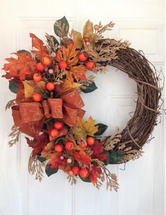 a wreath with autumn leaves and berries hanging on the front door to give as a decoration