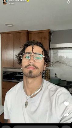 a man with glasses is taking a selfie in the kitchen while wearing headphones