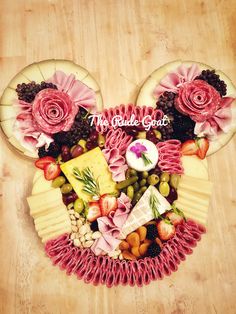 a mickey mouse head made out of cheese and fruit with flowers on it's ears