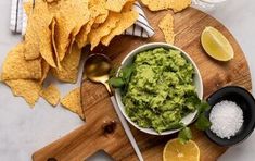 guacamole in a bowl surrounded by tortilla chips and limes