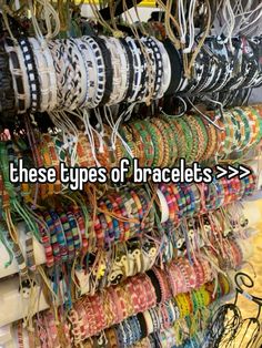 there are many bracelets hanging up on the wall in this store with words that read these types of bracelets > >