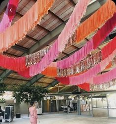 there is a woman that is walking under some pink and orange streamers hanging from the ceiling