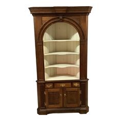 an old fashioned wooden china cabinet with arched glass doors and shelves on the top shelf