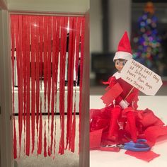 an elf is sitting on the floor next to some red streamers and a sign that says happy holidays