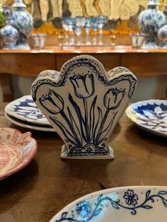 several plates and bowls on a table with vases in the background