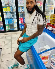 a man with dreadlocks sitting in front of a cooler