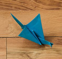 a blue origami bird sitting on top of a wooden floor