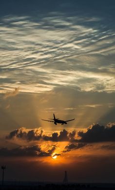 an airplane is flying in the sky at sunset