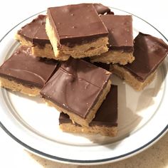 there are several pieces of chocolate and peanut butter bars on the plate, ready to be eaten