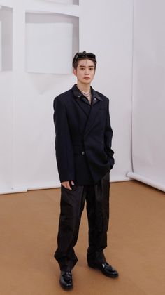 a young man standing in front of a white wall