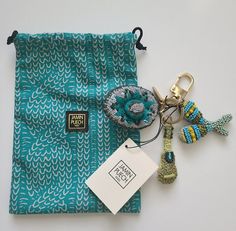 a blue bag with some keychains on it and a tag attached to it