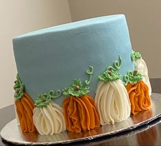 a blue and orange cake with white frosting pumpkins on it's sides