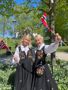 two girls dressed in traditional norwegian clothing holding flags