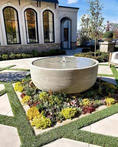 an outdoor fountain surrounded by grass and flowers