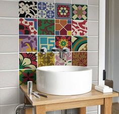 a bathroom sink sitting under a mirror next to a wall covered in colorful tile tiles