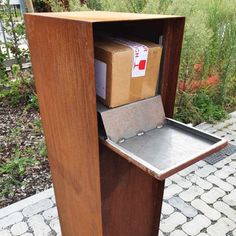 a wooden box that is sitting on top of a trash can with some boxes in it