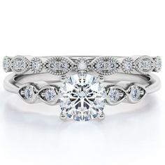 a white gold engagement ring set with a round brilliant cut diamond in the center and two matching wedding bands