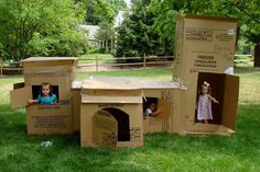 three cardboard boxes with children in them on the grass