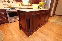 a large kitchen island in the middle of a hardwood floored area with stainless steel appliances