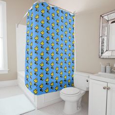 a bathroom with a toilet, sink and shower curtain that has clown fish on it