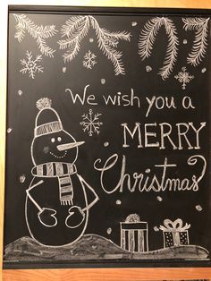 we wish you a merry christmas written on a blackboard with snowmen and presents