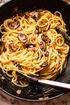 a pan filled with pasta and mushrooms on top of a table