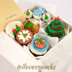 a box filled with lots of decorated cupcakes on top of a white table