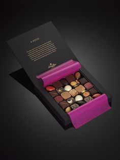 an open box of assorted chocolates on a black surface