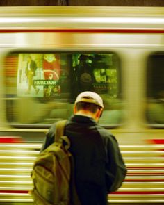 a man with a backpack is waiting for the subway to stop and look at him