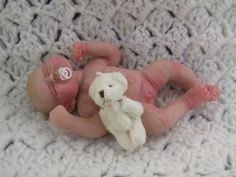 a baby laying on top of a blanket next to a teddy bear